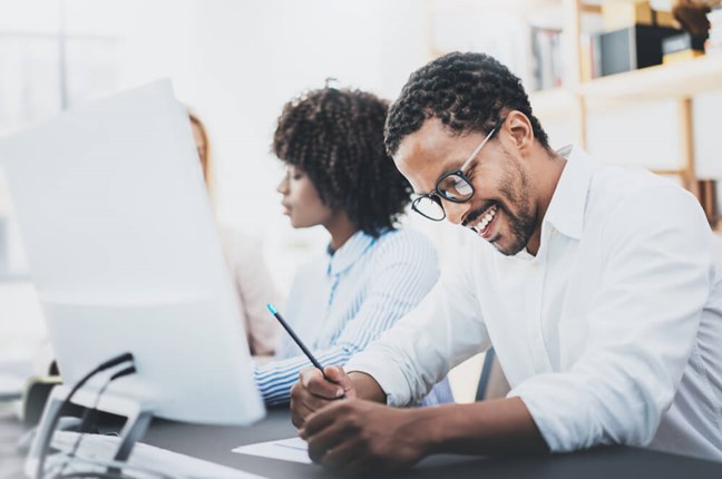 man sat at computer writing notes 