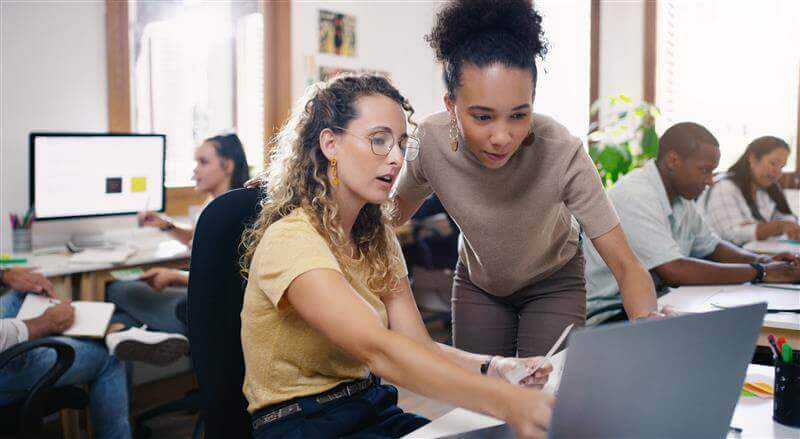 two female colleagues looking at computer screen together 